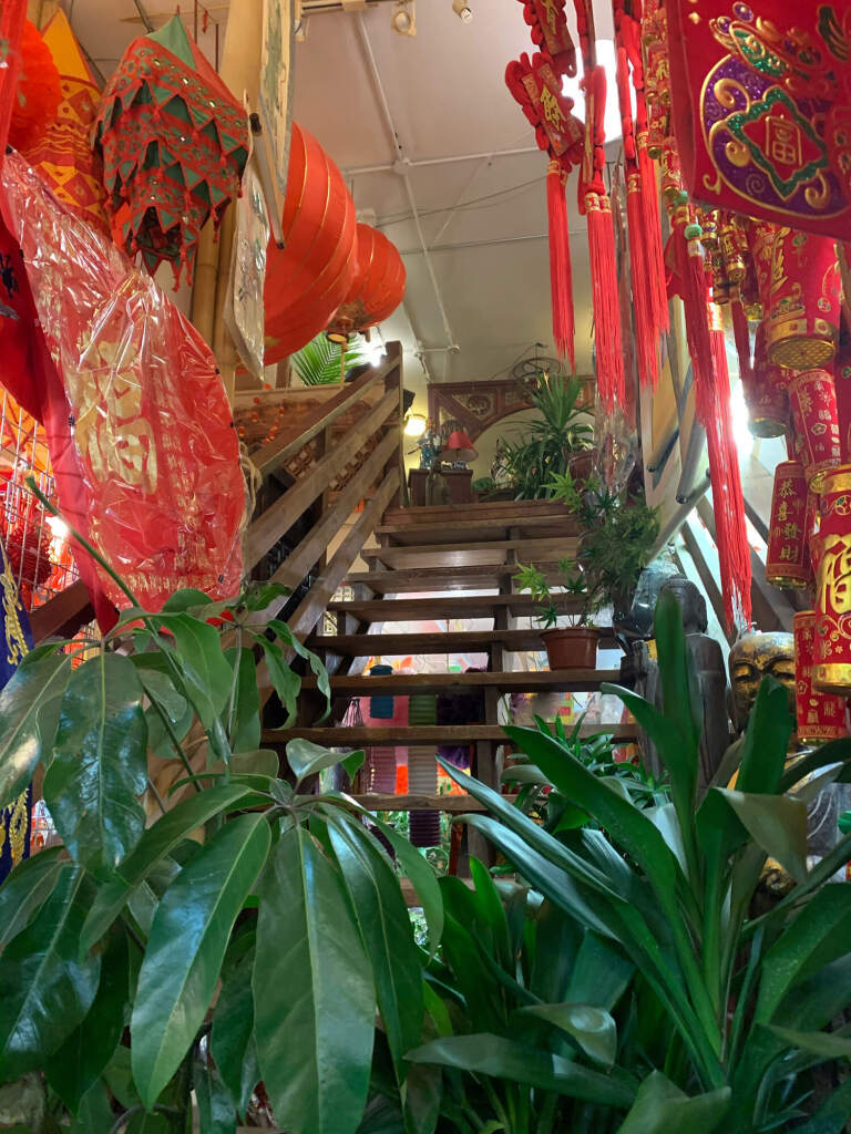 Bamboo Village, a plant, ceramic, joss, and bamboo goods store at 135 East Pender Street. Picture features colourful houseplants and spring decorations on the stairs in the centre of the store.